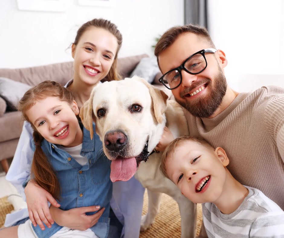A family with their labrador retriever smiling at the camera