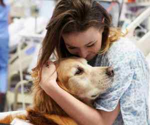 Photo of a hospital patient hugging a therapy dog